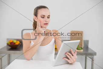 Thinking young woman using her tablet at table