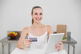 Smiling young woman using her tablet for online shopping