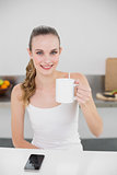 Happy young woman holding a mug looking at camera