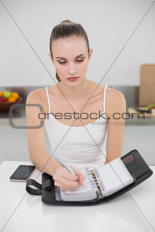 Serious young woman writing in a planner
