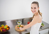 Pretty young woman preparing vegetables smiling at camera