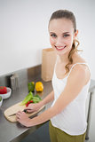 Happy young woman preparing vegetables smiling at camera