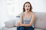 Shocked young woman sitting on couch
