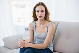 Stern young woman sitting on couch