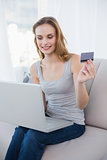 Pretty woman sitting on couch using laptop for online shopping