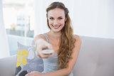 Happy young woman sitting on sofa watching tv
