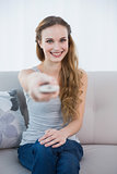 Smiling young woman sitting on sofa watching tv