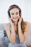 Content young woman sitting on sofa listening to music