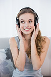Smiling young woman sitting on sofa listening to music