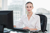 Serious businesswoman sitting at desk looking at camera