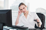 Frowning businesswoman sitting at desk hanging up phone