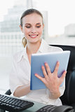 Happy businesswoman sitting at desk using tablet pc