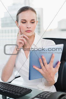 Thoughtful businesswoman sitting at desk using tablet pc