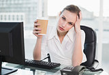 Stressed businesswoman holding disposable cup looking at camera