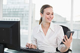 Smiling businesswoman holding calculator sitting at desk