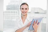 Smiling businesswoman using tablet pc looking at camera