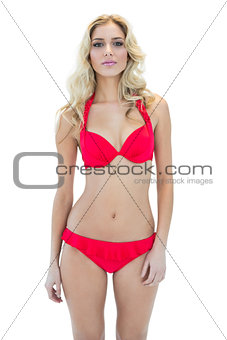 Pretty serious blonde model looking at camera wearing bikini