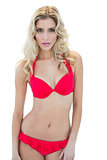 Attractive stern blonde model looking at camera in red bikini
