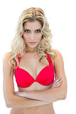 Challenging blonde model in red bikini posing with arms crossed