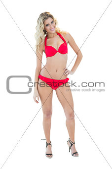 Cheerful pretty blonde model posing with hand on hips wearing red bikini