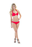 Beautiful smiling blonde model posing with hand on hips wearing red bikini