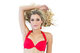 Attractive blonde model wearing red bikini posing with arm over head
