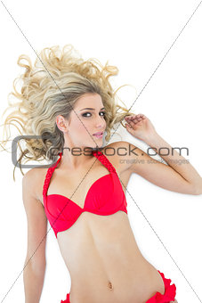 Passionate blonde model wearing red bikini smiling at camera