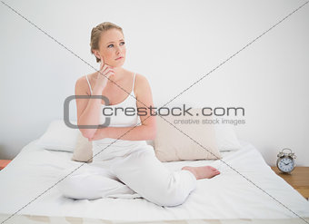 Natural thoughtful blonde sitting in bed