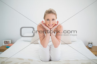 Natural happy blonde sitting on bed