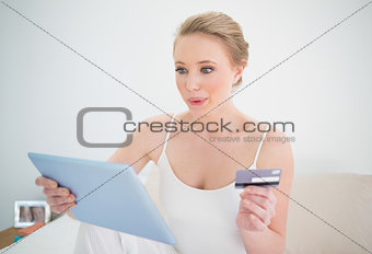 Natural happy blonde holding tablet and credit card