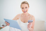 Natural cheerful blonde holding tablet and credit card