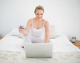 Natural cheerful blonde using credit card and laptop