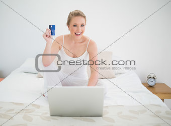 Natural happy blonde using credit card and laptop
