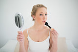 Natural blonde holding mirror and using brush