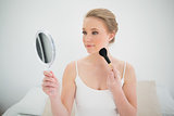 Natural content blonde holding mirror and using brush