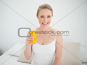 Natural smiling blonde holding glass of orange juice