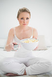 Natural stern blonde holding remote and popcorn