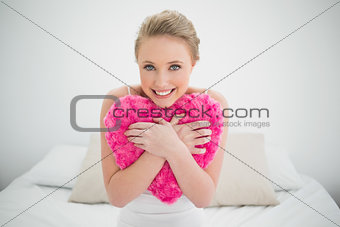 Natural smiling blonde holding heart pillow