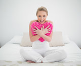 Natural cheerful blonde holding heart pillow