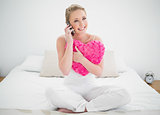 Natural content blonde holding heart pillow and phoning