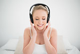 Natural smiling blonde listening to music with closed eyes