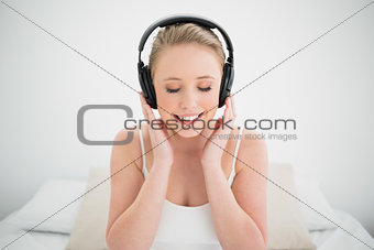 Natural smiling blonde listening to music with closed eyes