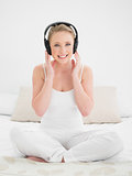 Natural smiling blonde listening to music with headphones
