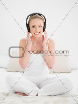 Natural smiling blonde listening to music with headphones