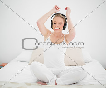 Natural cheerful blonde listening to music and arms in the air