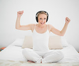 Natural smiling blonde listening to music and arms in the air