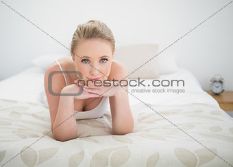 Natural content blonde lying on bed touching her chin