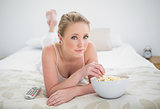 Natural content blonde lying on bed and eating popcorn