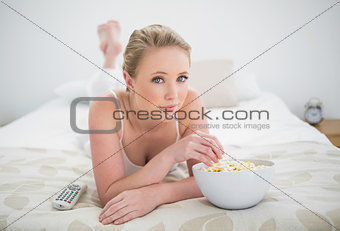 Natural content blonde lying on bed and eating popcorn