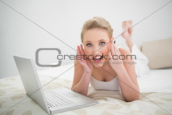 Natural excited blonde holding credit card and looking at camera